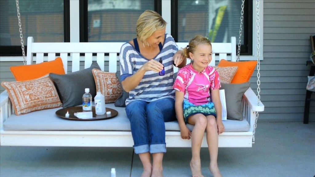 woman and girl sitting on white bench on porch with colorful pillows and tray of vinegar and rubbing alcohol