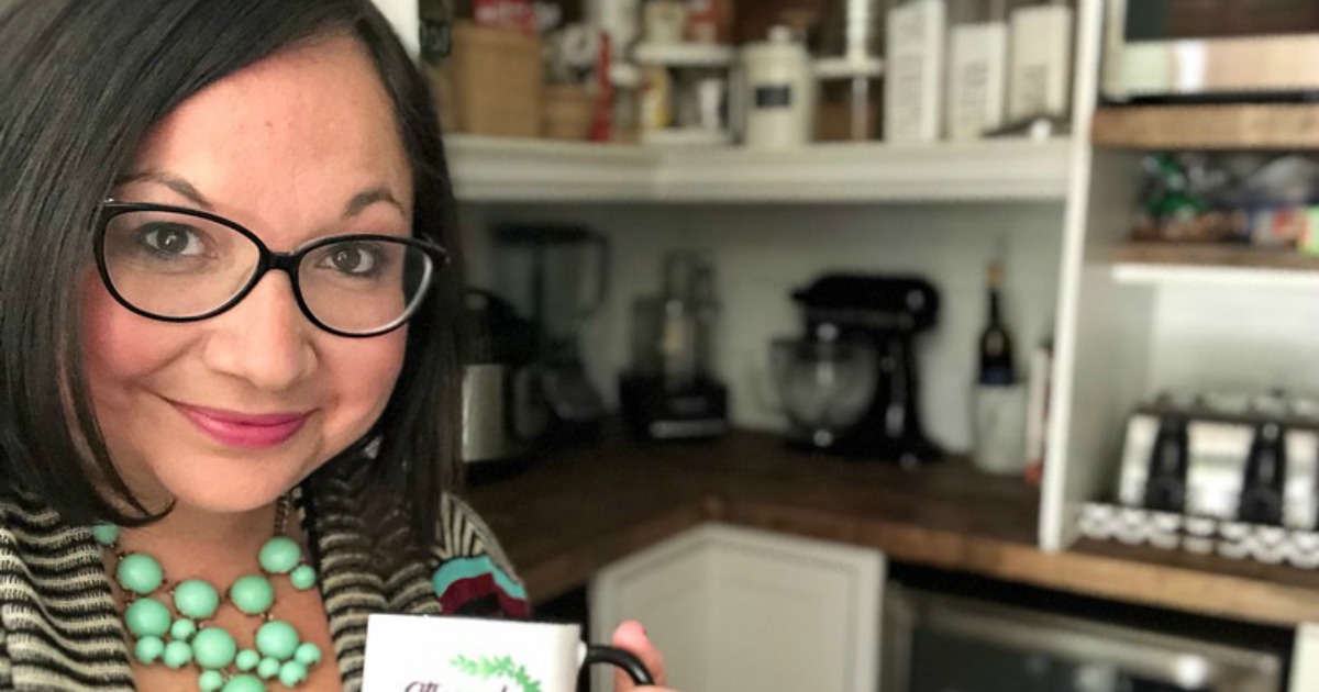 Lina holding a coffee cup in front of her open pantry door