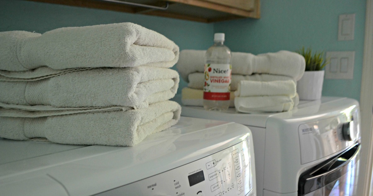 white folded stacks of towels on a dryer near a bottle of white vinegar