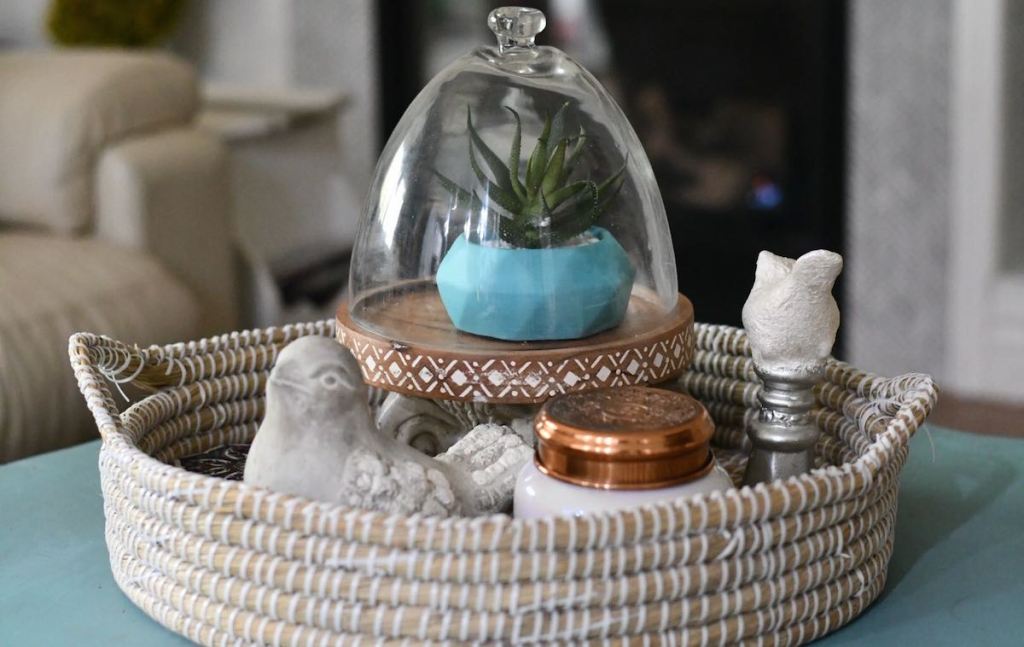 shallow basket tray with plant and candle sitting on counter