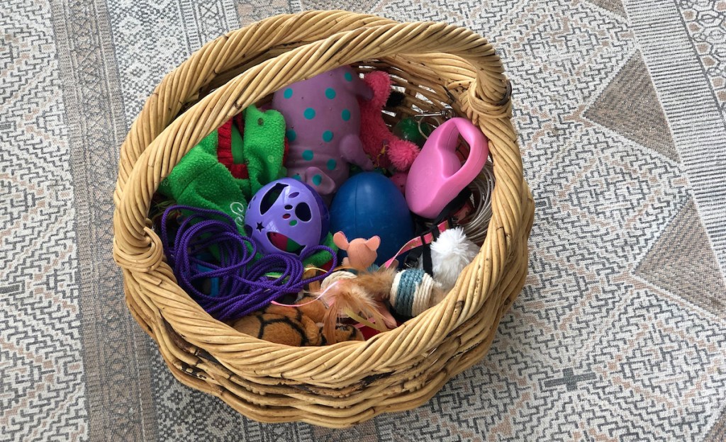 colorful pet toys in a round wicker basket