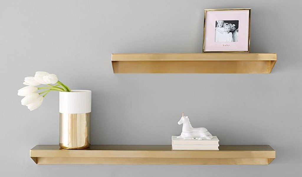 two gold brass shelves on wall with accessories