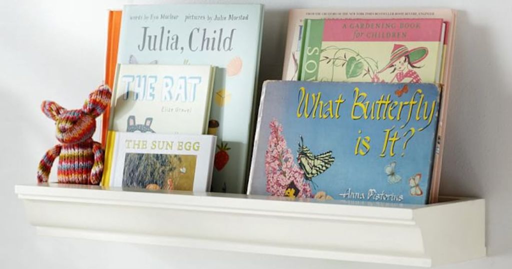 various different books on white floating shelf with plush toy