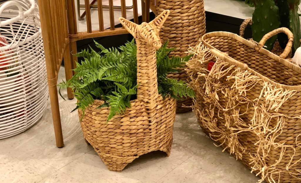 llama basket with a green faux plant inside sitting on the floor