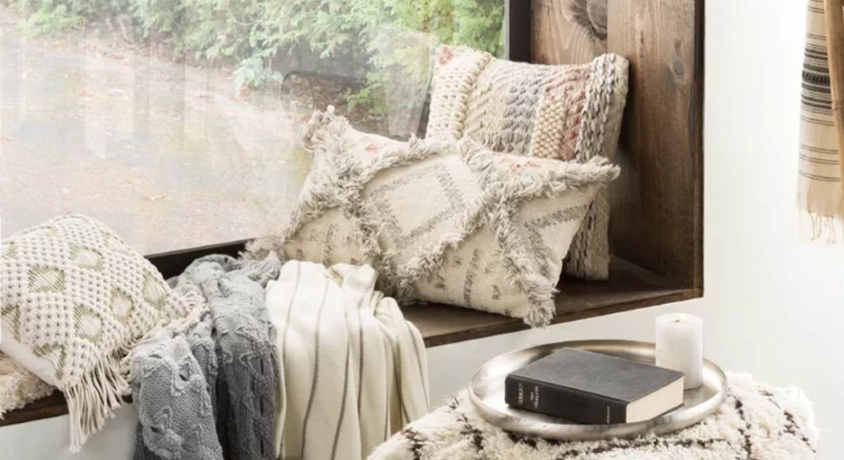 lumbar wool fringe pillow on window sill with other pillows throw blankets books on an ottoman