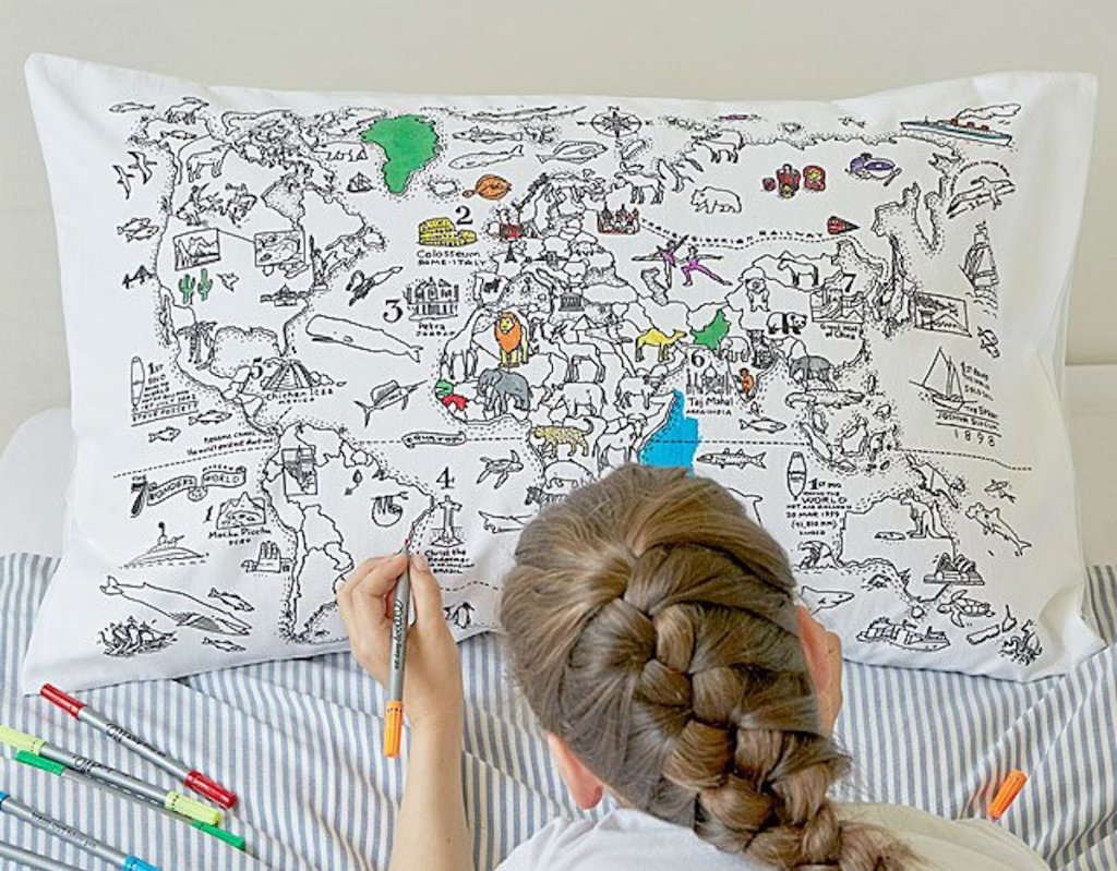 girl with braided hair coloring on map pillowcase