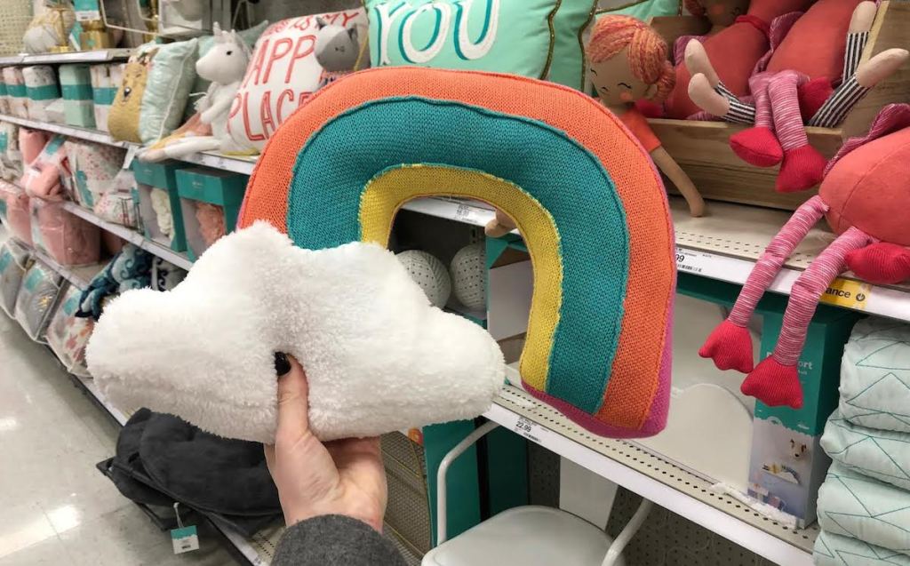 hand holding a rainbow pillow in store aisle 