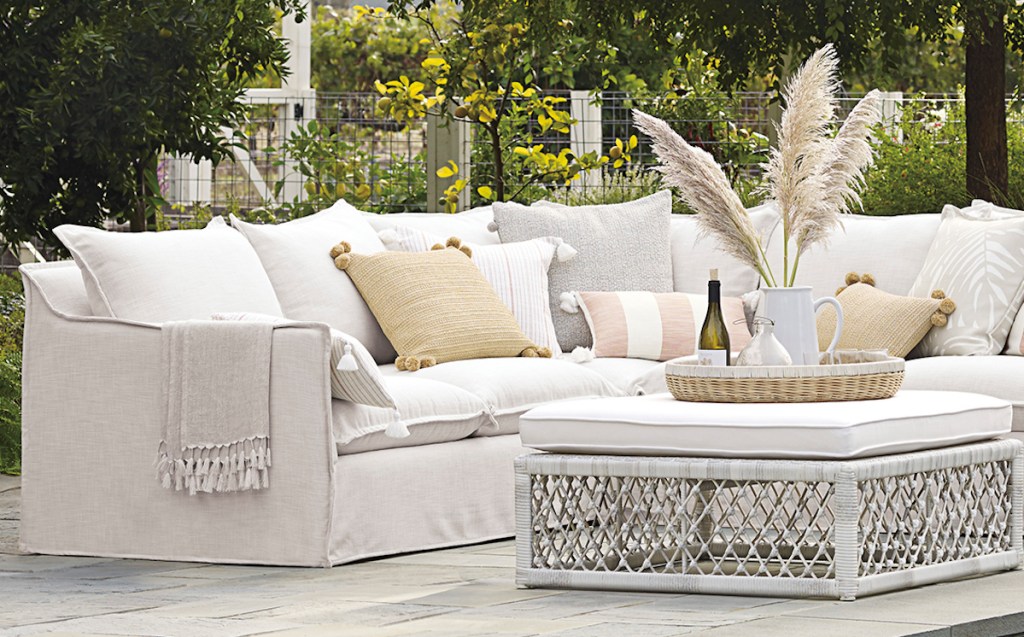 outdoors photo of off white couch by pool with pillows yellow and striped