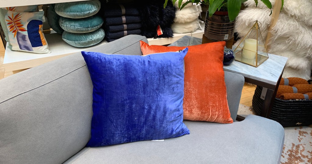 royal blue and bright orange velvet pillows sitting on a gray couch