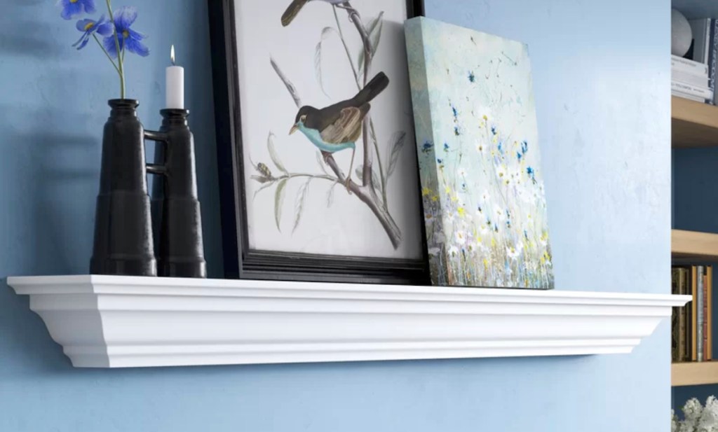traditional white shelf with molding decorated with candles and picture artwork