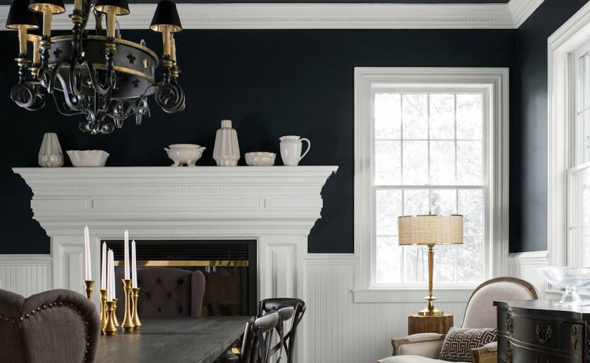 dining room with black walls and white trim with fireplace mantel and gold decor items