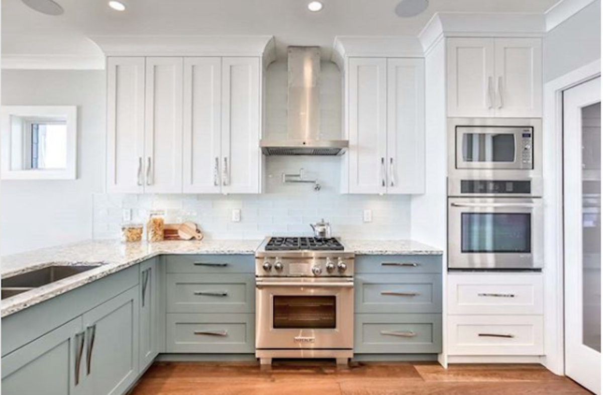 white and sage blue kitchen cabinets with stainless steel appliances