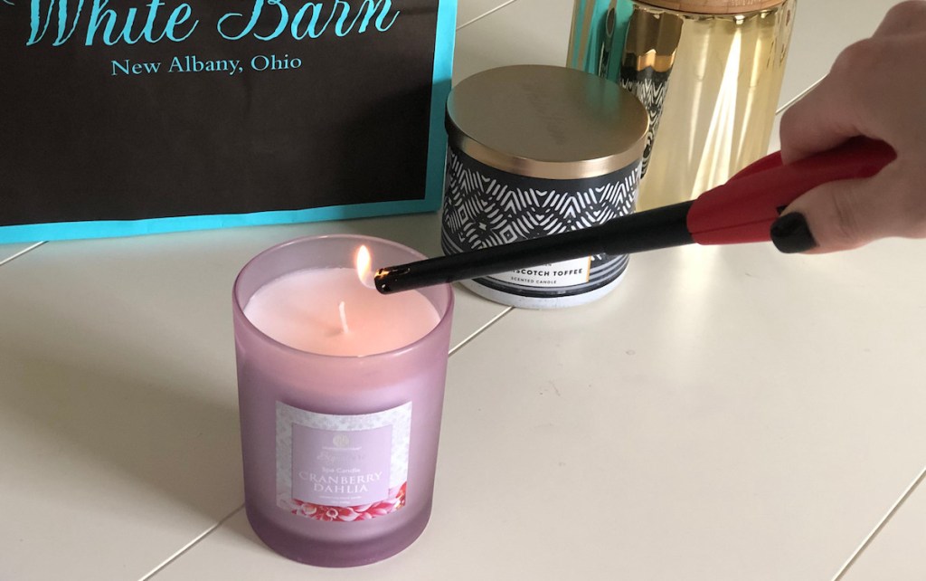 stick lighter lighting a purple candle with candles in the background