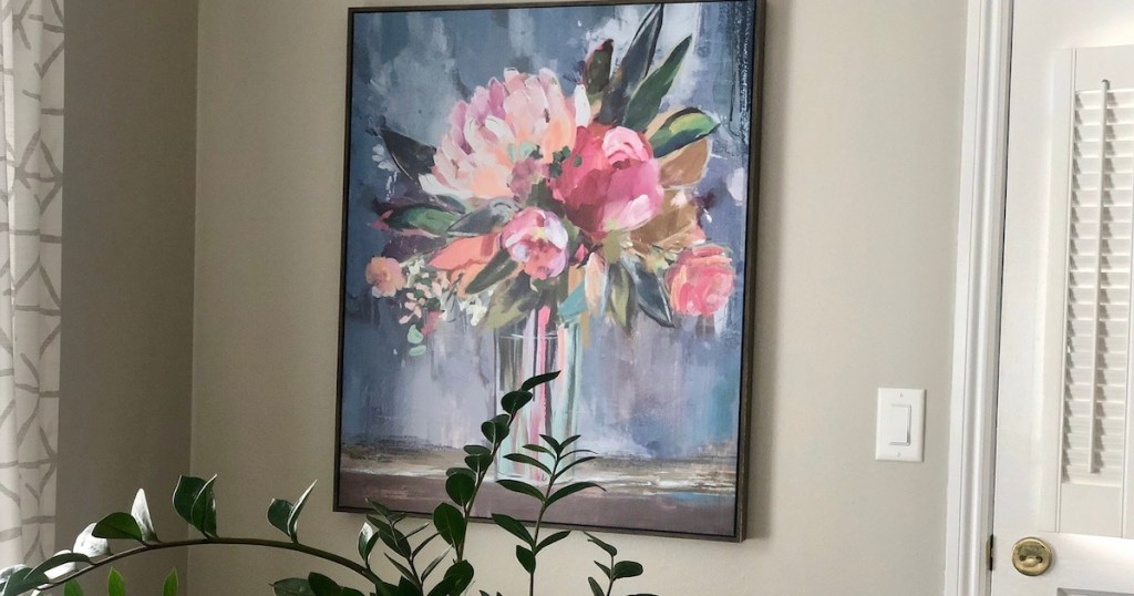 picture of floral artwork on beige wall with green stems in front