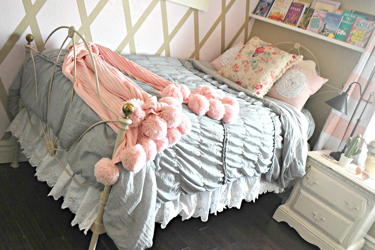girls bed with gray comforter and pink pom pom blanket