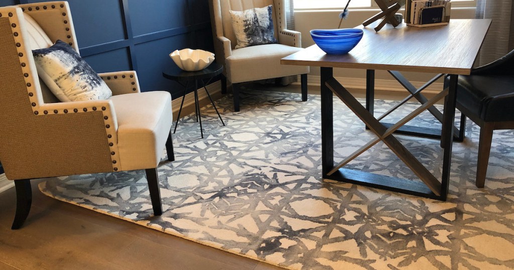 office room with dark blue wall two cream beige chairs and geometric rug on floor