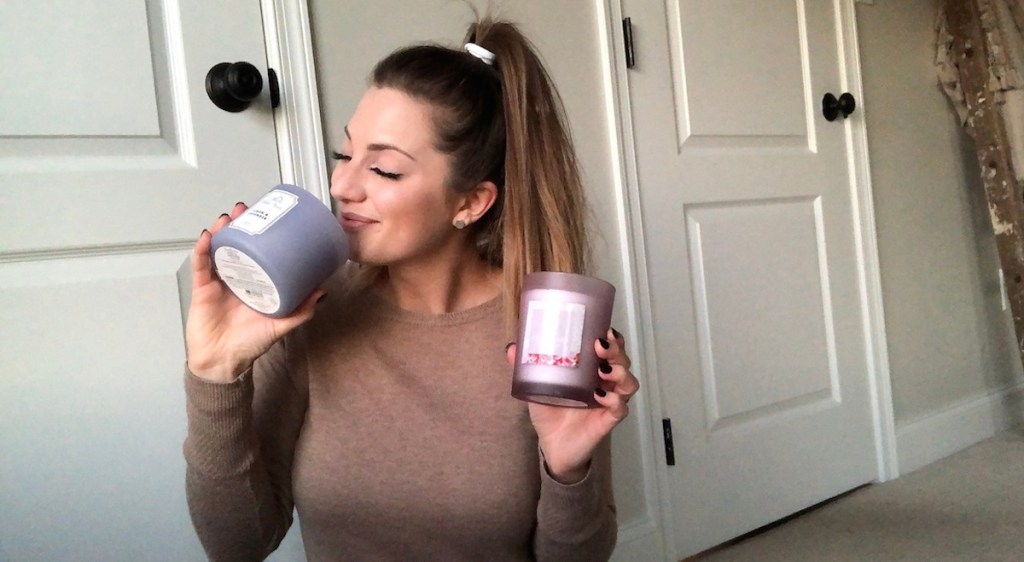 sara smelling purple candle while holding two candles in hand