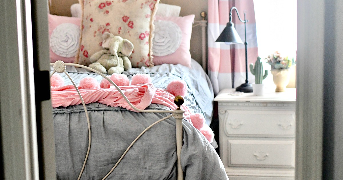 close up of girls bedroom with pink pom blanket on top of bed