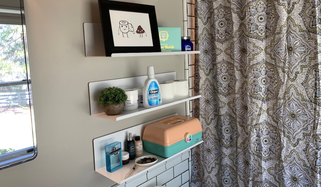 white metal wall shelves in a bathroom next to medallion shower curtain