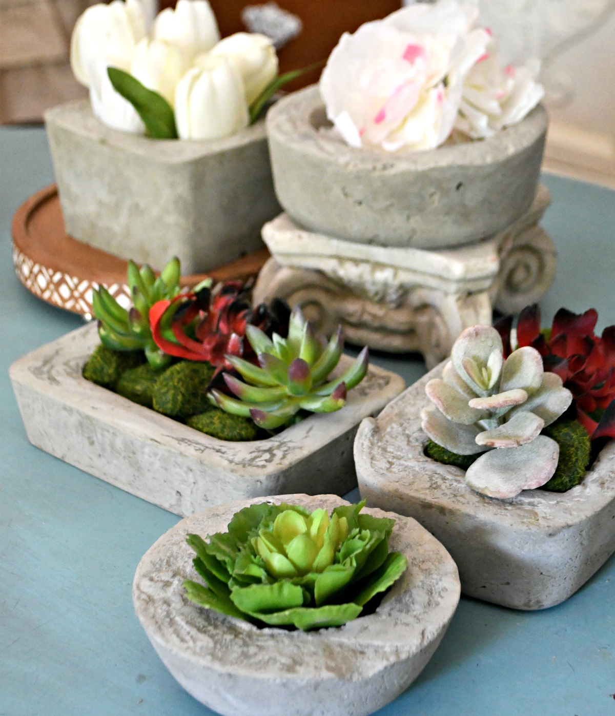 tabletop with a collection of diy cement planters and concrete planters styled with flowers and succulents