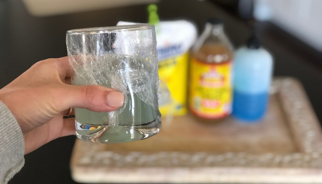 hand holding glass with blue liquid covered with plastic