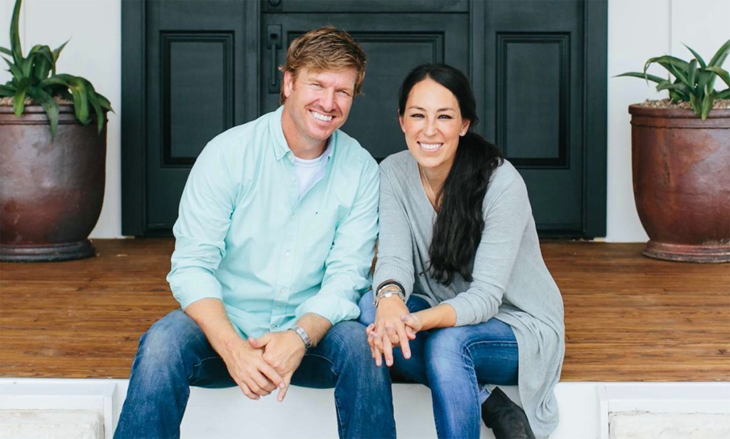 chip and joanna gaines sitting next to each other smiling on porch steps
