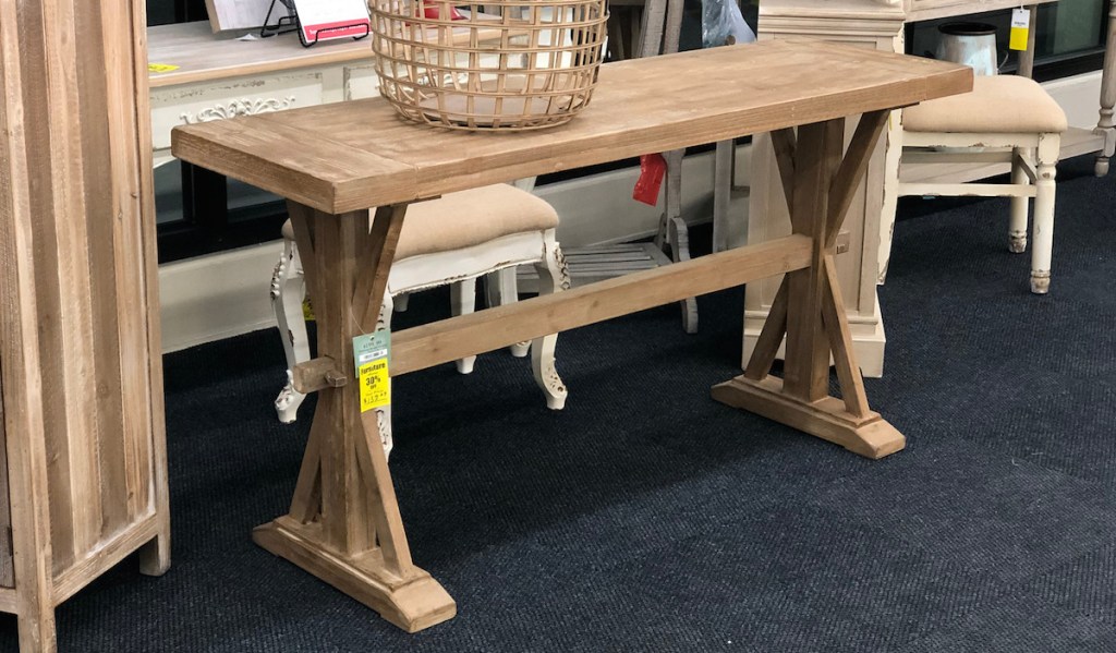 natural colored wood console table with basket on top sitting in store