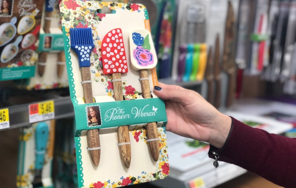 hand holding set of colorful rubber spatulas in store aisle 