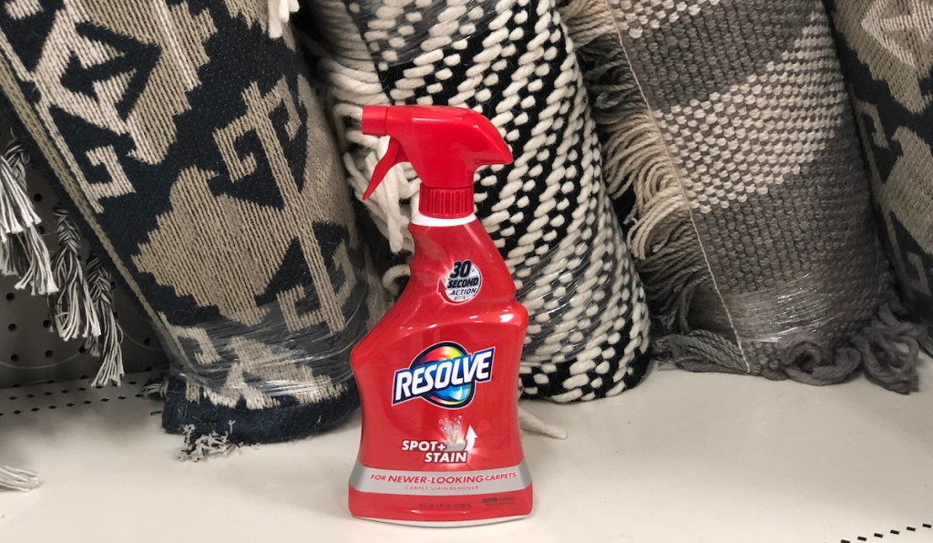 red spray bottle of resolve sitting on a metal shelf with black and cream rugs in background
