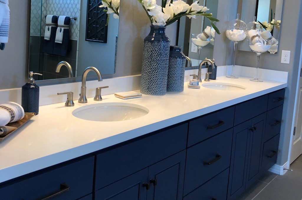 bathroom double vanity with navy blue cabinets and white countertops with flowers
