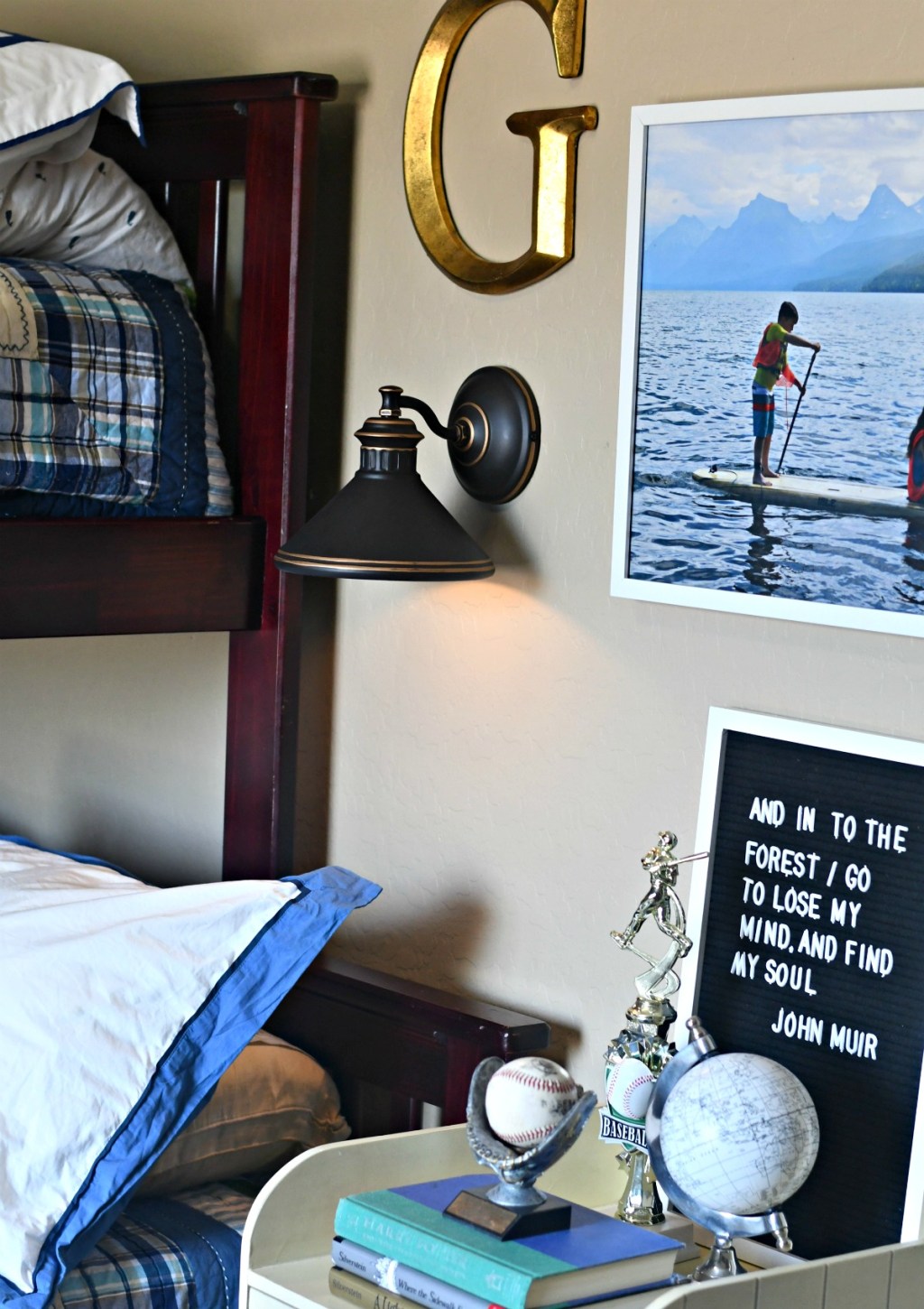 corner of bunk bed with wall sconce lighting up the wall and other wall decor