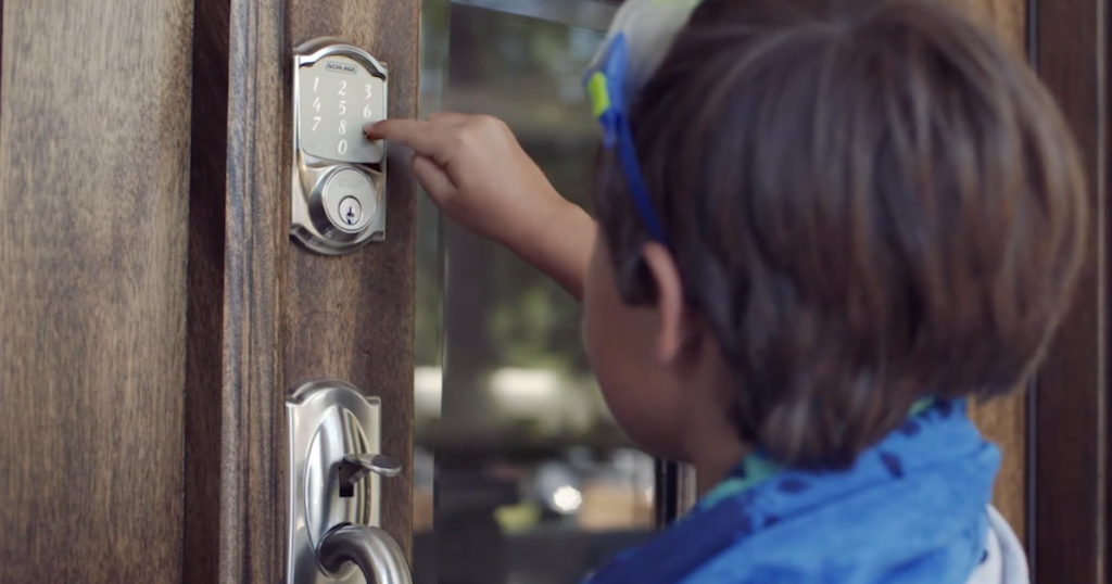 boy pushing digital keyless door lock keypad buttons on wood and glass front door
