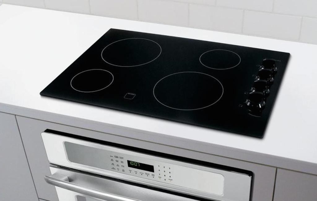 black flat smooth cooktop on white countertop with white cabinets and backsplash