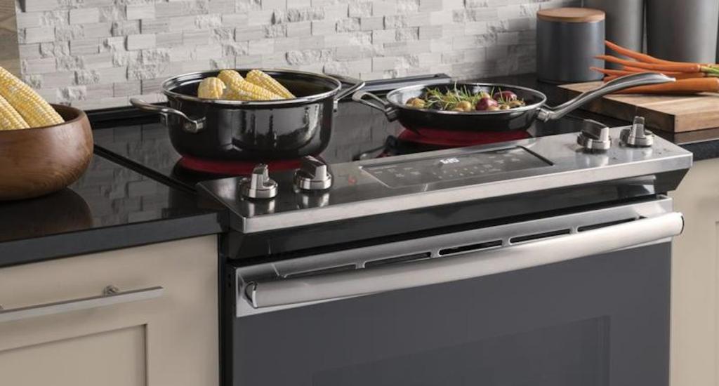 electric stainless steel and black range with pot and pan cooking corn on the cob 