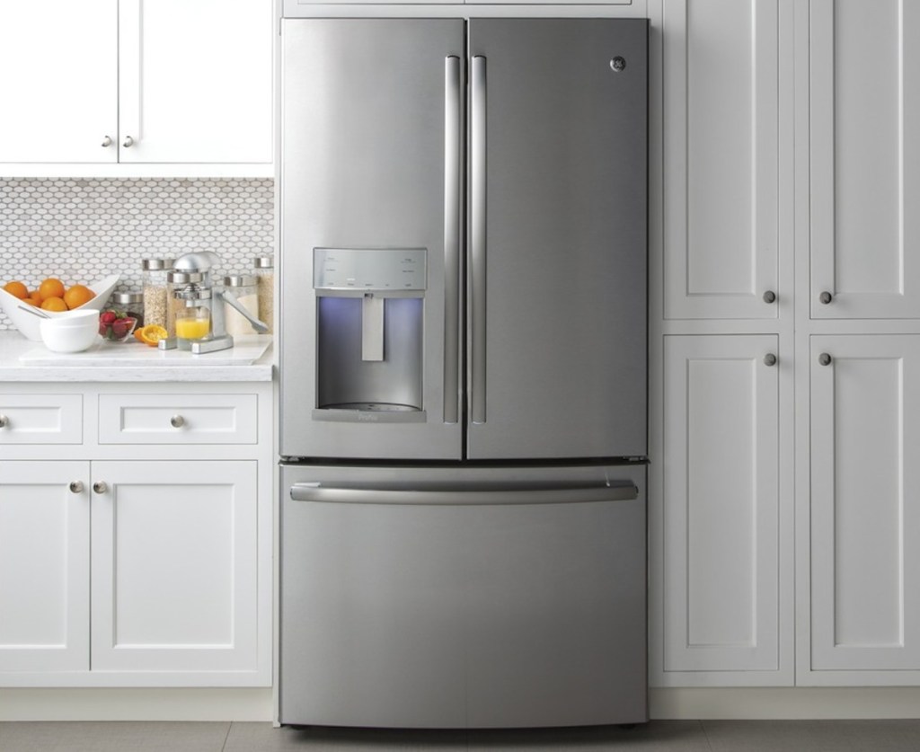 stainless steel french door fridge with white shaker kitchen cabinets surrounding it