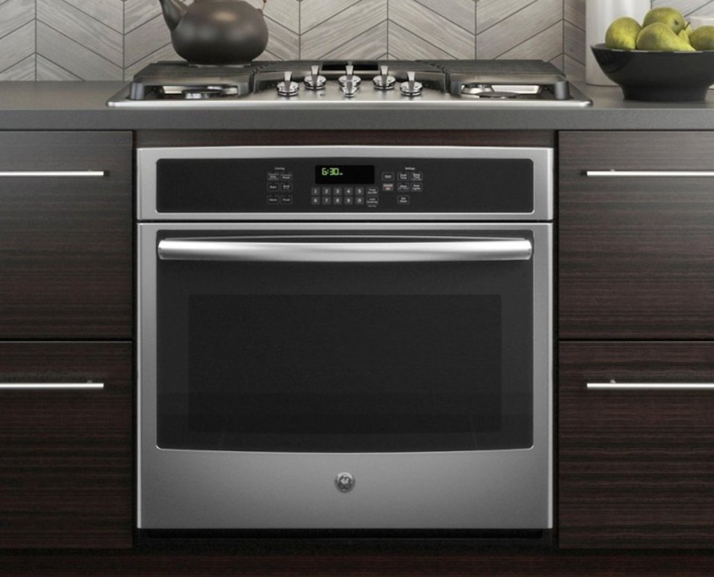 stainless stell oven with dark brown modern cabinets range on counter and tea kettle on top