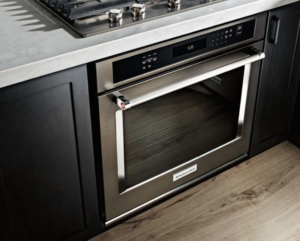 stainless steel kitchenaid oven with black cabinets and gray countertops 