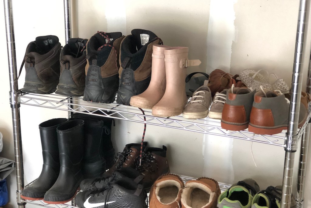 various styles of boots and shoes on metal shoe rack
