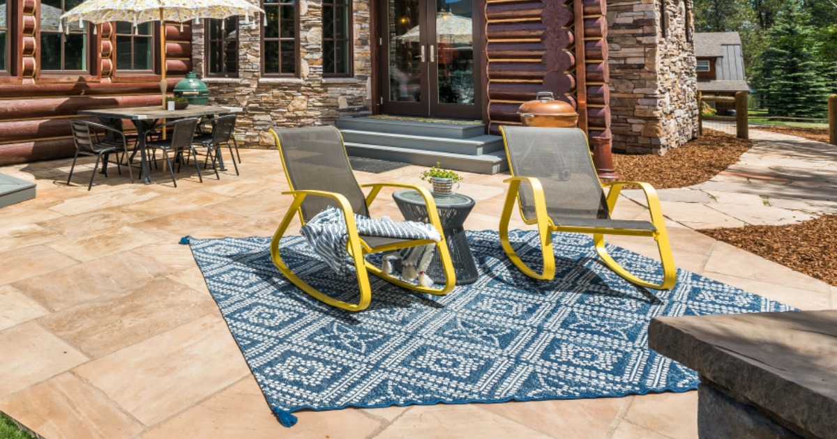 blue diamond rug on patio with two chairs on rug and house and table in background