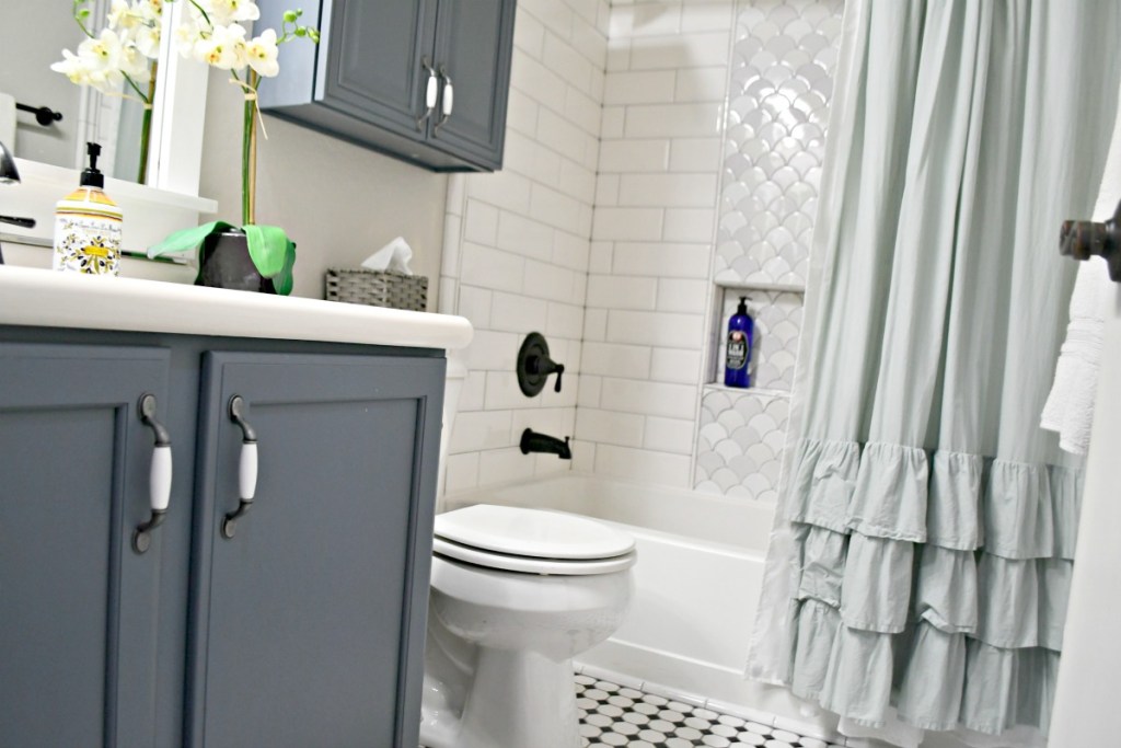 bathroom with blue cabinets and ruffle shower curtain 