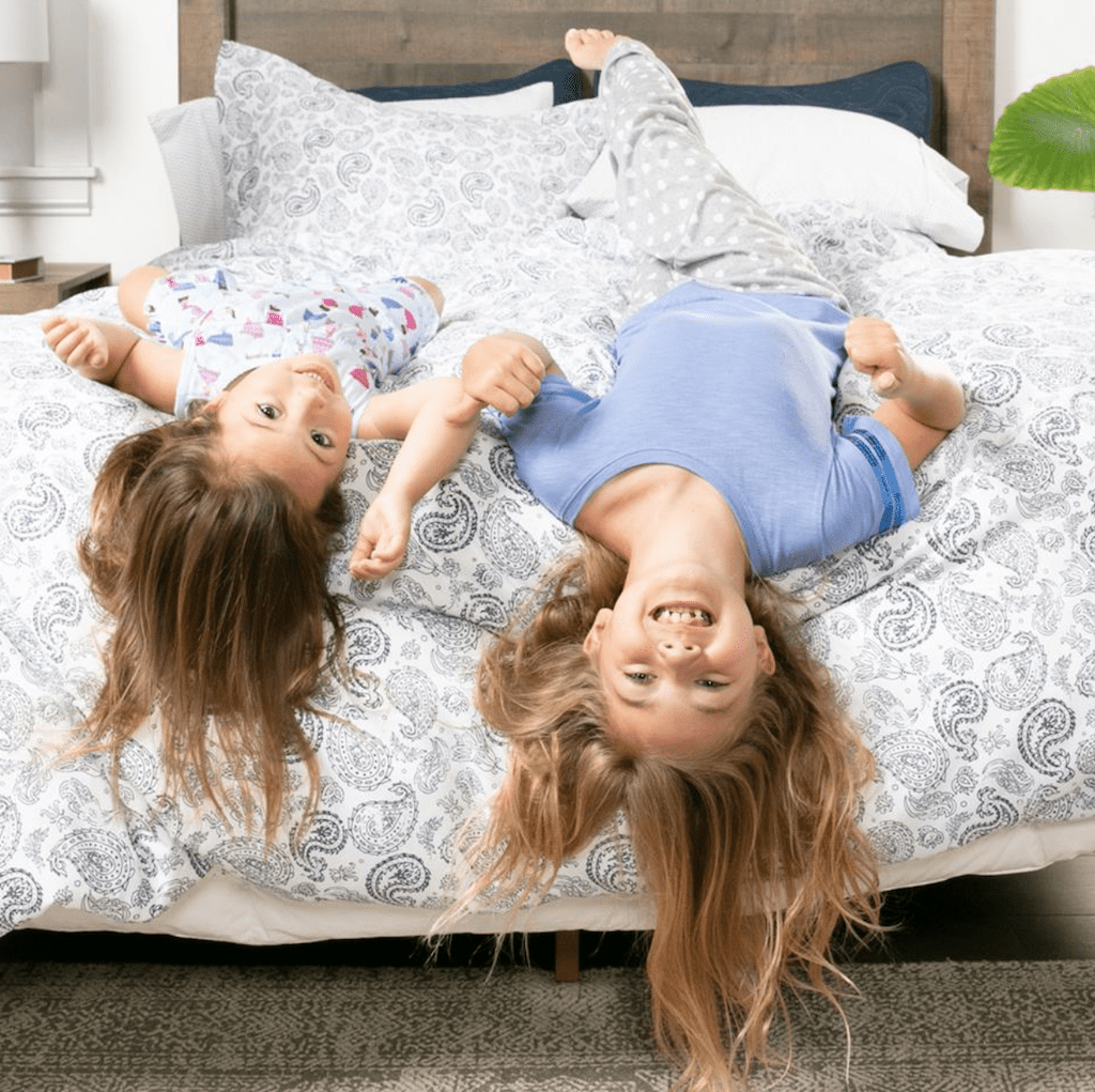 girls laying on bed on top of patterned duvet cover 