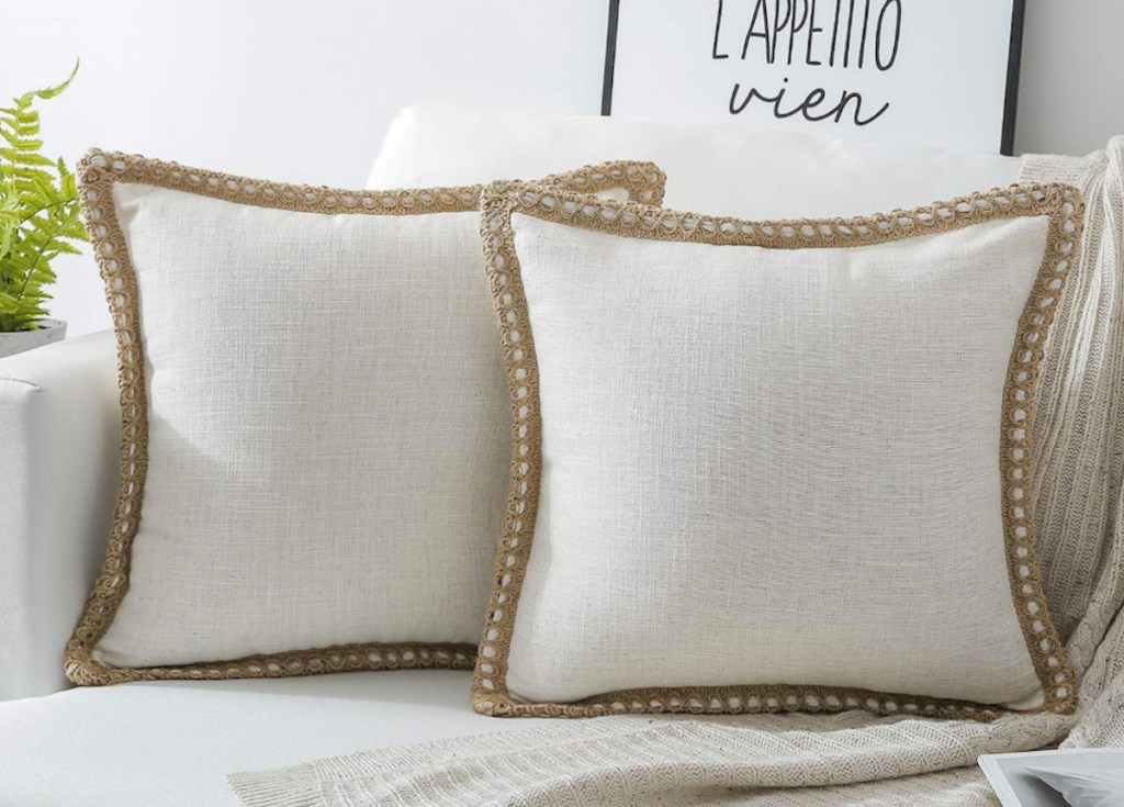 two white bordered pillows on white couch