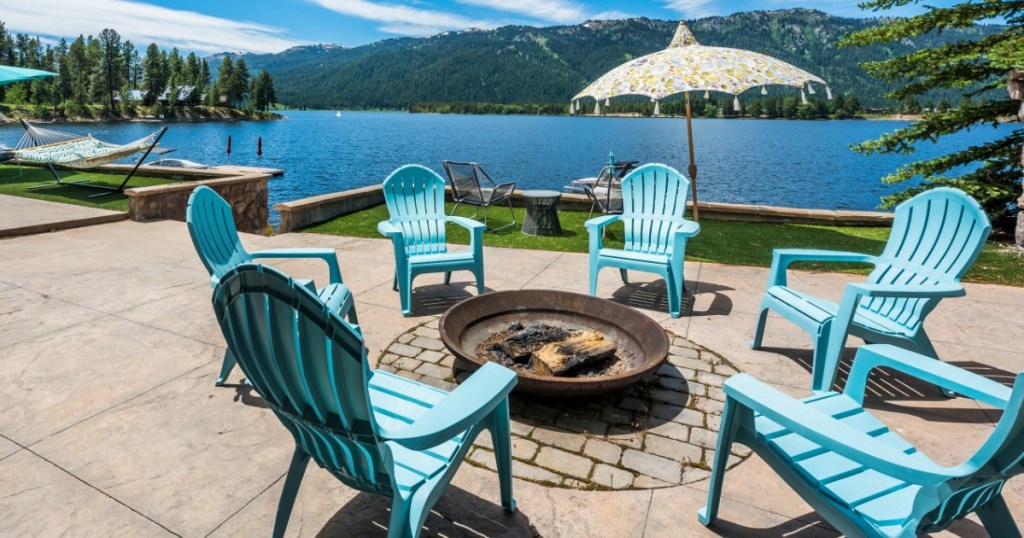 blue chairs sitting around a firepit on a patio with lake in the background