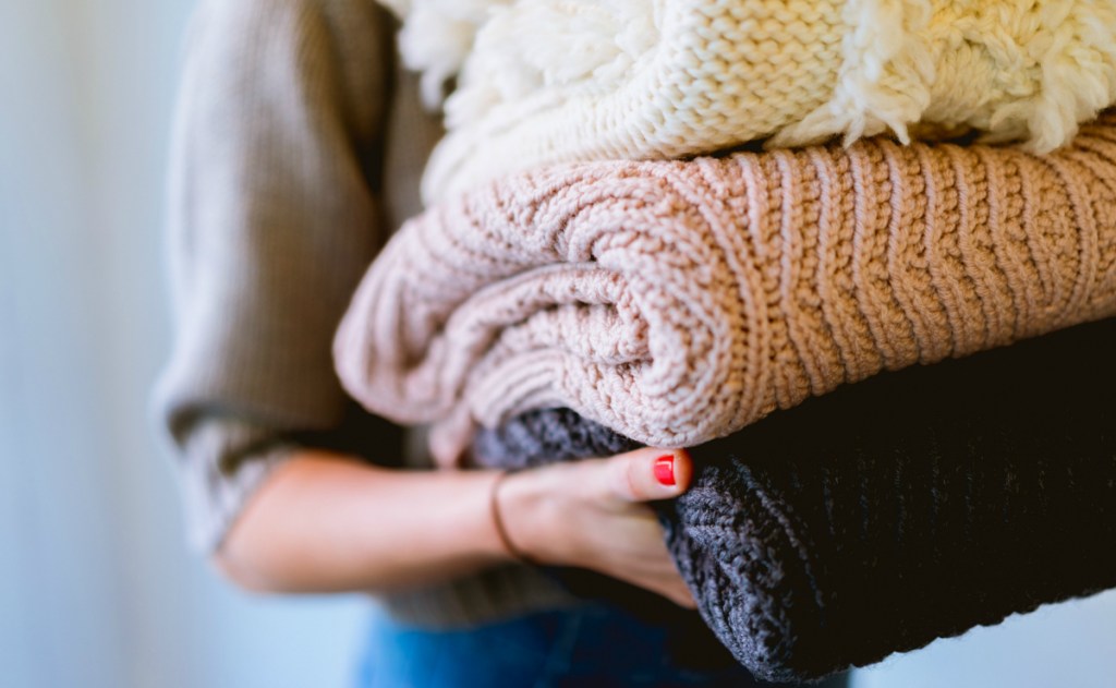 girl holding stack of blankets