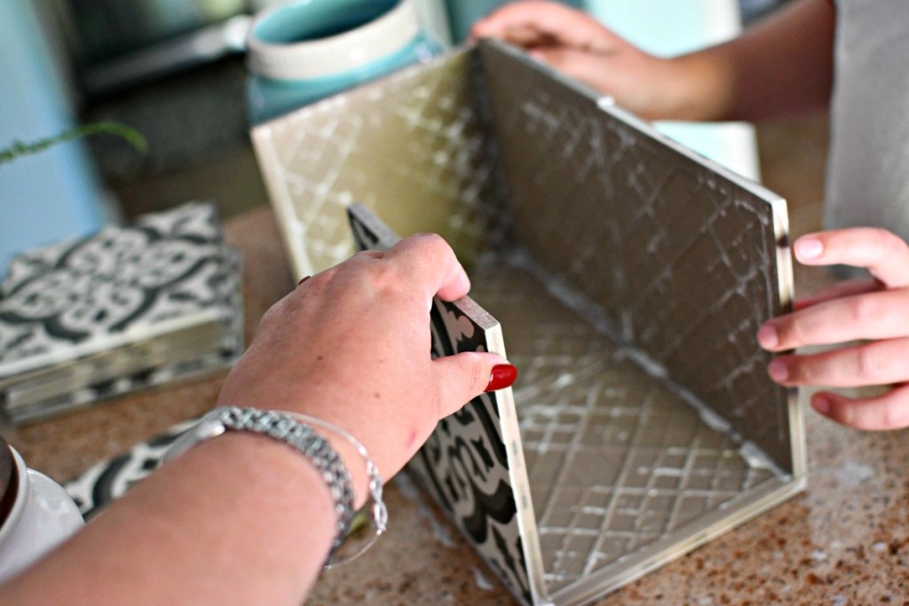 holding up glued tiles to make a planter