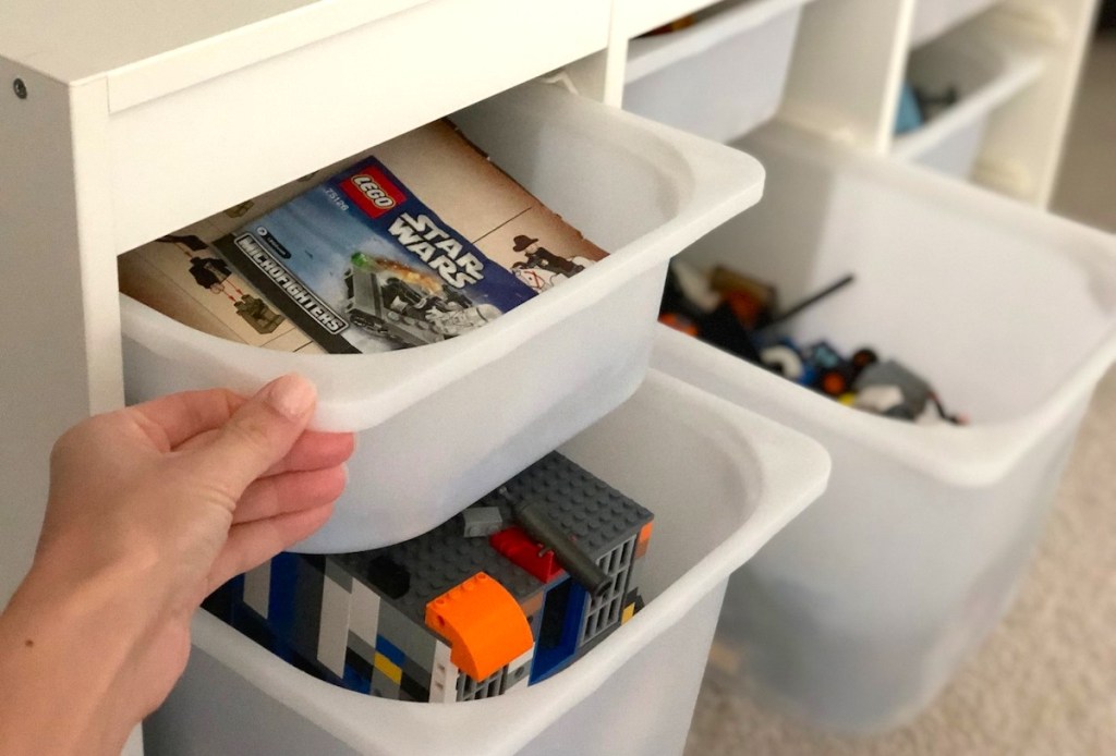 hand pulling white plastic bin with legos
