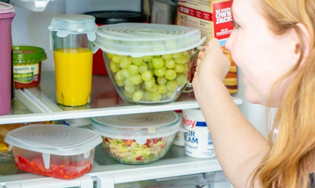 woman grabbing bowl of grapes from fridge
