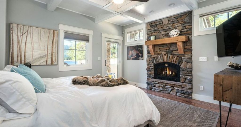 blue room with white bed and stone fireplace