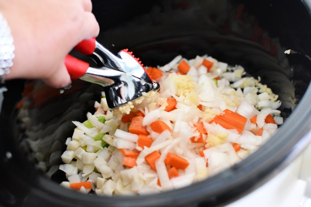 Adding garlic to slow cooker using garlic press.