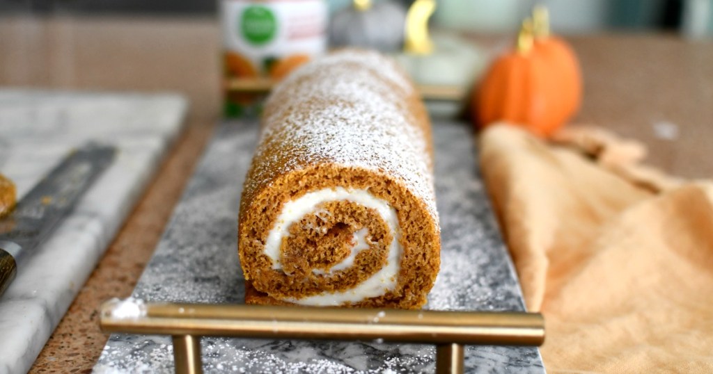 pumpkin roll on a cutting tray with powdered sugar